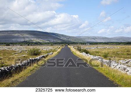 Stock Photography - A road lined with a stone wall at the edge of the burren; County galway ireland. Fotosearch