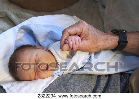 Picture - A sleeping newborn clutching a man's thumb; Willimantic connecticut united states of america. Fotosearch
