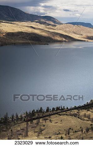 Stock Photo - A small train makes it's way along the shore of kamloops lake; Kamloops british columbia canada. Fotosearch
