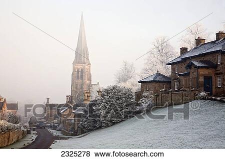 Stock Photo - A tall church steeple in the fog within a neighbourhood in winter; Edensor derbyshire england. Fotosearch