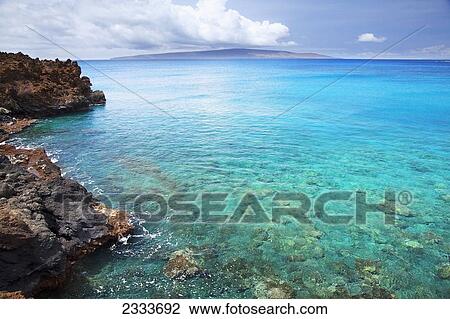 A view of La Perouse Bay with clear water and coral with Kooholawae in the distance; Maui, Hawaii, United States of America View Large Photo Image Stock Image - A view of La Perouse Bay with clear water and coral with Kooholawae in the distance; Maui, Hawaii, United States of America. Fotosearch