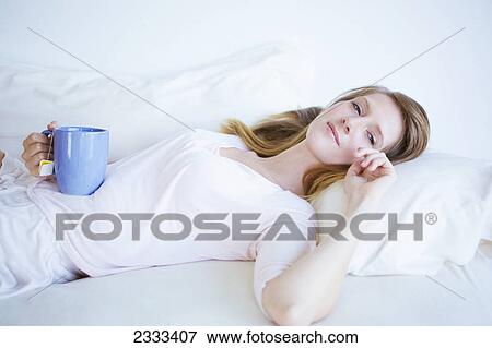 A woman laying in bed with a cup of tea; Kauai hawaii united states of america View Large Photo Image Stock Photo - A woman laying in bed with a cup of tea; Kauai hawaii united states of america. Fotosearch