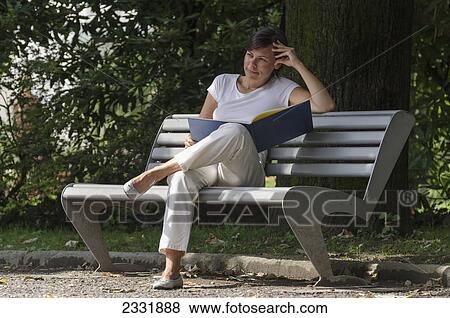 A woman sits reading on a bench; Locarno ticino switzerland View Large Photo Image Stock Photo - A woman sits reading on a bench; Locarno ticino switzerland. Fotosearch