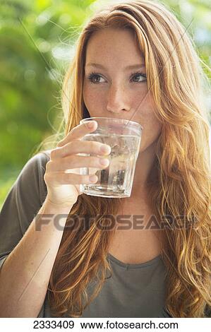 Stock Photo - A woman taking a drink of water from a glass; Kauai hawaii united states of america. Fotosearch