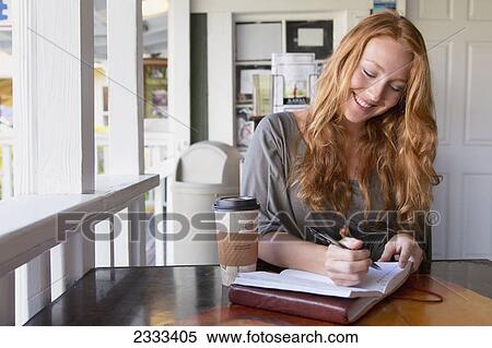 A woman writing notes in a coffee shop; Kauai hawaii united states of america View Large Photo Image Stock Photography - A woman writing notes in a coffee shop; Kauai hawaii united states of america. Fotosearch