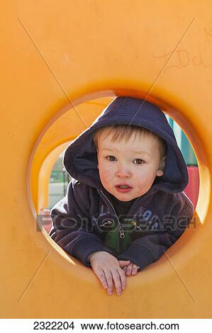 A young boy looks through a hole on playground equipment; Willimantic connecticut united states of america View Large Photo Image Picture - A young boy looks through a hole on playground equipment; Willimantic connecticut united states of america. Fotosearch