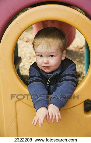 A young boy looks through a hole on playground equipment; Willimantic connecticut united states of america View Large Photo Image Stock Photo - A young boy looks through a hole on playground equipment; Willimantic connecticut united states of america. Fotosearch