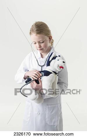 A young girl wearing a doctor's coat and stethoscope examining a stuffed toy puppy; Anchorage alaska united states of america View Large Photo Image Stock Image - A young girl wearing a doctor's coat and stethoscope examining a stuffed toy puppy; Anchorage alaska united states of america. Fotosearch
