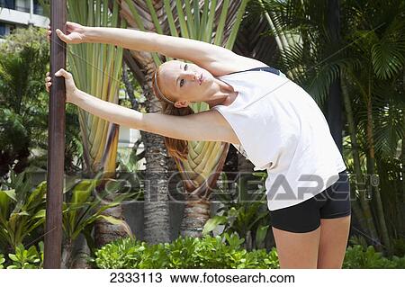 Stock Image - A young woman stretches on a pole; Honolulu oahu hawaii united states of america. Fotosearch
