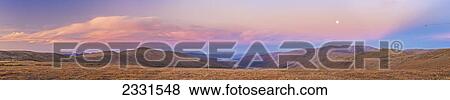 Stock Photo - Alpenglow lights the clouds above eagle summit along the steese highway north of fairbanks as the moon rises in autumn; Fairbanks interior alaska united states of america. Fotosearch