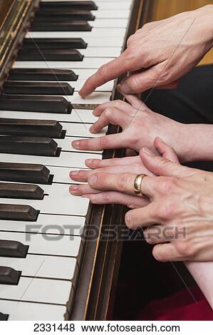An older woman's hands showing a six year old girl how to play the piano; Anchorage alaska united states of america View Large Photo Image Stock Photo - An older woman's hands showing a six year old girl how to play the piano; Anchorage alaska united states of america. Fotosearch