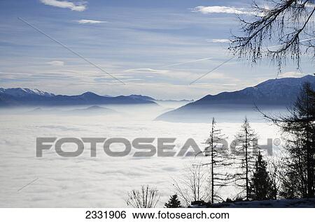 Billows of fog rolling over the landscape; Locarno ticino switzerland View Large Photo Image Stock Photograph - Billows of fog rolling over the landscape; Locarno ticino switzerland. Fotosearch