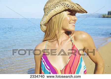 Stock Image - Blond haired woman with sunhat at the beach; Kauai, Hawaii, United States of America. Fotosearch