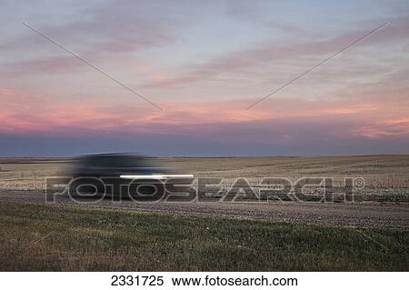 Blur of a vehicle traveling down a dirt road beside a field; Saskatchewan canada View Large Photo Image Stock Photography - Blur of a vehicle traveling down a dirt road beside a field; Saskatchewan canada. Fotosearch