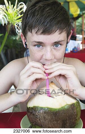 Stock Photograph - Boy drinking coconut milk from a shell; Thailand. Fotosearch
