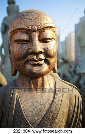 Picture - Bronze Faced Buddha Statue Glowing In Warm Light; Beijing China. Fotosearch