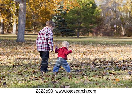 Stock Image - Brother and sister walking in a park in autumn; Edmonton alberta canada. Fotosearch