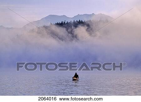 Stock Photograph - Canoeist On Alta Lake, With Mountains And Mist. Fotosearch