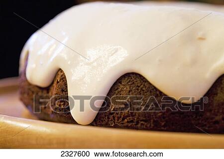 Stock Image - Close up of a glazed chocolate cake on a wooden plate; Calgary alberta canada. Fotosearch