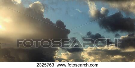 Stock Image - Clouds in a blue sky highlighted by sunlight; Waterville county kerry ireland. Fotosearch