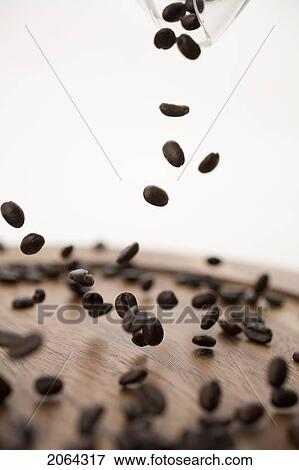 Stock Photo - Coffee Beans Dropping Onto Wooden Plate. Fotosearch