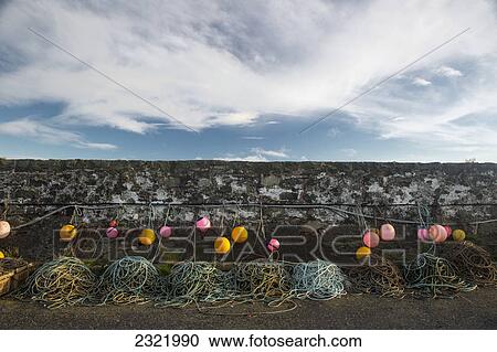 Stock Image - Colourful Buoys And Ropes Hanging Along A Stone Wall; Dumfries And Galloway Scotland. Fotosearch