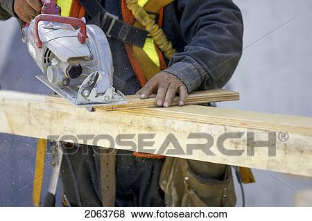 Construction Worker Cutting A Piece Of Wood With A Skill Saw.; Canada, Ontario, Hamilton (Composting Facility) View Large Photo Image Stock Photo - Construction Worker Cutting A Piece Of Wood With A Skill Saw.; Canada, Ontario, Hamilton (Composting Facility). Fotosearch