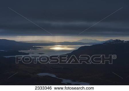 Stock Photograph - Crepuscular rays (beams of sunlight) coming through clouds as seen from near the summit of ben damph; Torridon highlands scotland. Fotosearch