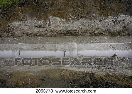 Stock Photo - Drainage Pipe Half Buried In Earth; Canada, Ontario, Hamilton (Composting Facility). Fotosearch