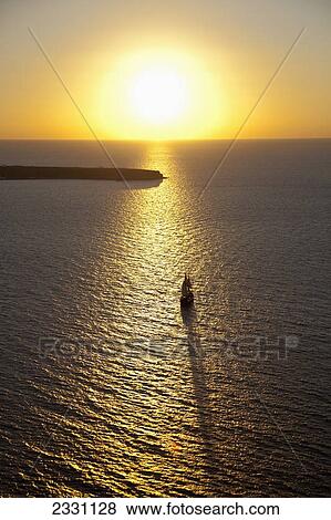 Stock Photo - Glowing sunlight reflected on the aegean sea at dusk; Oia greece. Fotosearch