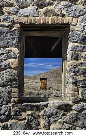 Gold mining ghost town outhouse in distance framed through stone building window; Bodie california united states of america View Large Photo Image Stock Photo - Gold mining ghost town outhouse in distance framed through stone building window; Bodie california united states of america. Fotosearch