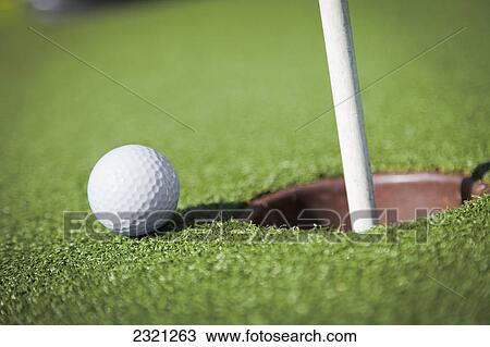 Stock Image - Golf Ball Sits Next To The Hole; Kissimmee Florida United States Of America. Fotosearch