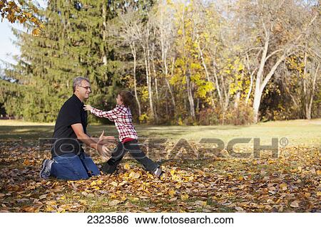 Stock Photograph - Grandfather and grandson playing in a park in autumn; Edmonton alberta canada. Fotosearch