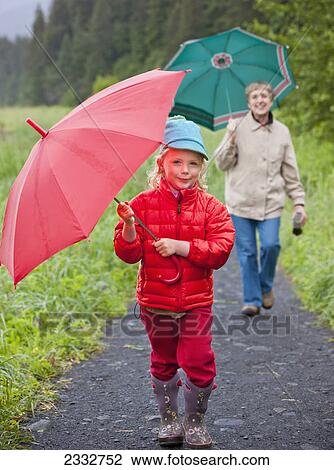 Grandmother and granddaughter playing with their umbrella while walking up the path from the beach at Lowell Point on a rainy day, summer, Seward, Southcentral Alaska, USA View Large Photo Image Stock Image - Grandmother and granddaughter playing with their umbrella while walking up the path from the beach at Lowell Point on a rainy day, summer, Seward, Southcentral Alaska, USA. Fotosearch