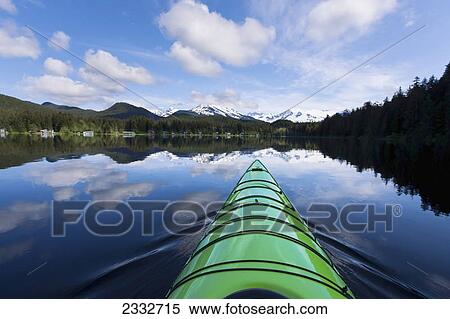 Stock Photography - Green kayak on the tranquil water of auke lake with mendenhall glacier and towers in the distance; Alaska united states of america. Fotosearch
