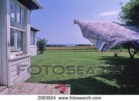 Picture - Handmade Quilt Blowing On Laundry Line, Farmhouse And Ocean Visible, Pei. Fotosearch