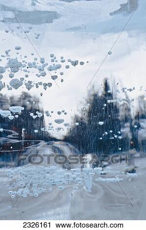 Stock Image - Ice formed on the camera lens with a view of a tree lined road; Anchorage alaska united states of america. Fotosearch
