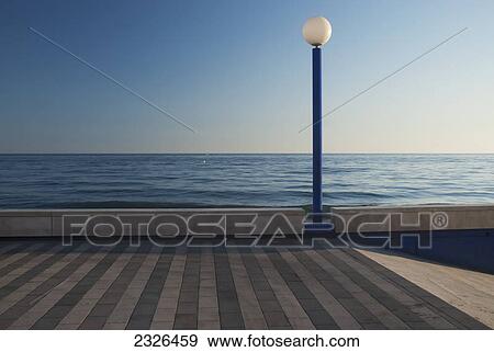 Lamp post along a sea promenade with a blue horizon; Malaga andalusia spain View Large Photo Image Stock Photo - Lamp post along a sea promenade with a blue horizon; Malaga andalusia spain. Fotosearch
