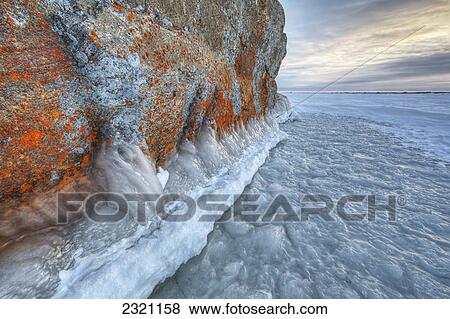 Stock Photo - Large Lichen Covered Rock In A Frozen Lake Situated On The Flats Beside Hudson's Bay; Manitoba Canada. Fotosearch