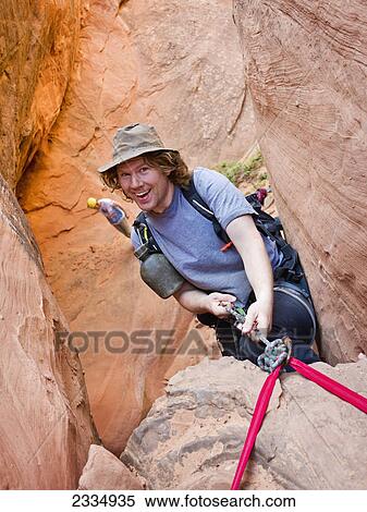 Stock Photography - Man rappelling into a slot canyon; Hanksville utah united states of america. Fotosearch