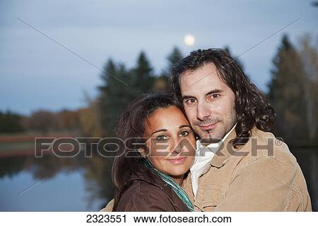 Stock Image - Married couple outdoors at dusk with a lake in the background; Edmonton alberta canada. Fotosearch