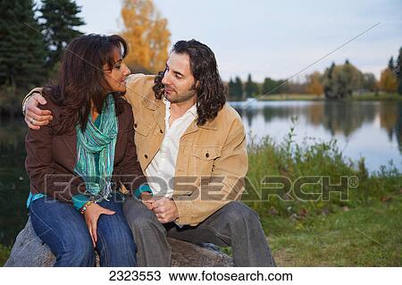 Stock Image - Married couple outdoors at dusk with a lake in the background; Edmonton alberta canada. Fotosearch