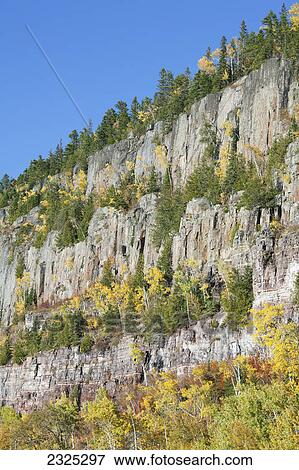 Stock Photo - Mountain cliffs with trees growing on the ledges in autumn colours; Thunder bay ontario canada. Fotosearch