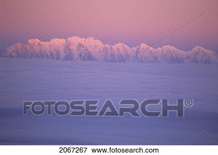 Stock Photo - Mountain Ridge Called The Steeples In Evening Light With Cloud Inversion, East Kootenays, B. C.. Fotosearch