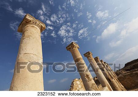 Stock Image - Old columns in a row against a blue sky with clouds; Paphos cyprus. Fotosearch