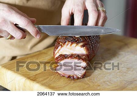 Stock Photo - Oven Roasted Ham Being Sliced On Cutting Board With Large Knife. Fotosearch