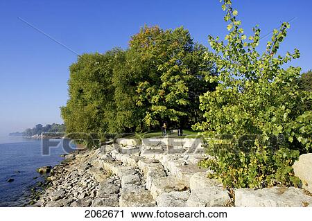 Stock Image - Person At Edge Of Tiered Rock Embankment Along Lake Ontario, Burlington. Fotosearch