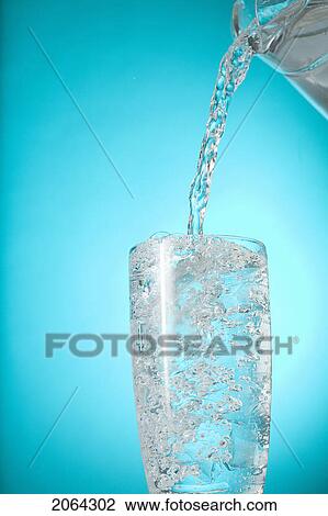 Stock Image - Pitcher Of Water Pouring Into Very Full Clear Glass. Fotosearch