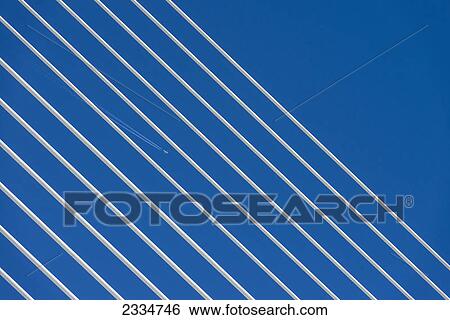 Stock Photograph - Plane flying high above detail of a suspension bridge; Valencia, Spain. Fotosearch