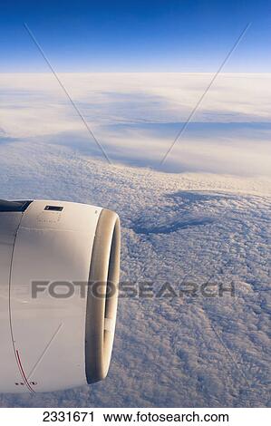 Stock Image - Plane flying over clouds. Fotosearch